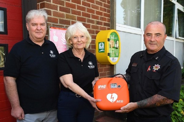 St John Scotland volunteers Stuart Mathewson and Margaret McAdam present a defibrillator to Knightswood Fire Station, Glasgow, June 2019